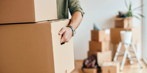 Close-up of man carrying cardboard boxes while relocating into n